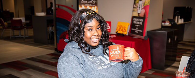 Student posing with a LEAD mug.