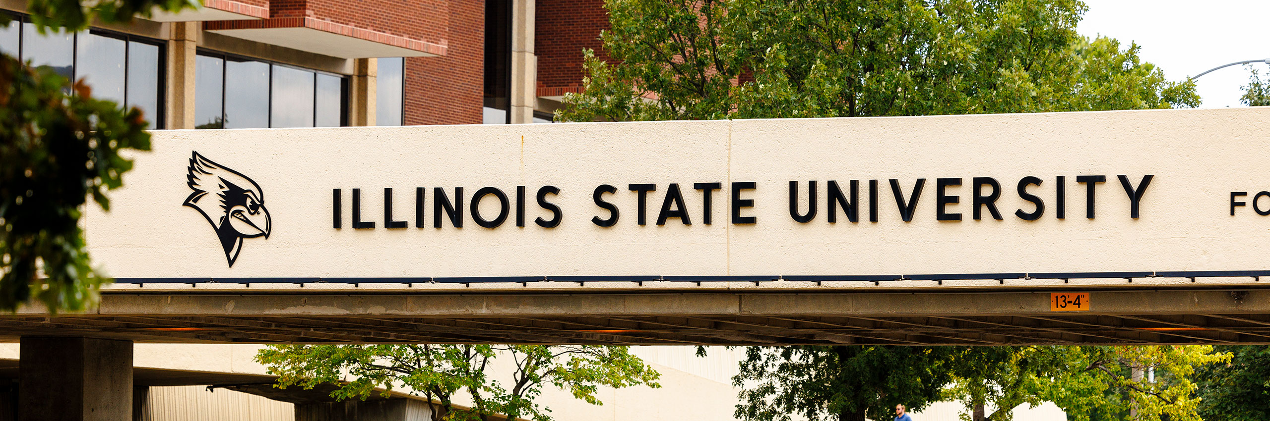 Close-up photo of the walking bridge over College Avenue with Illinois State University on the side.